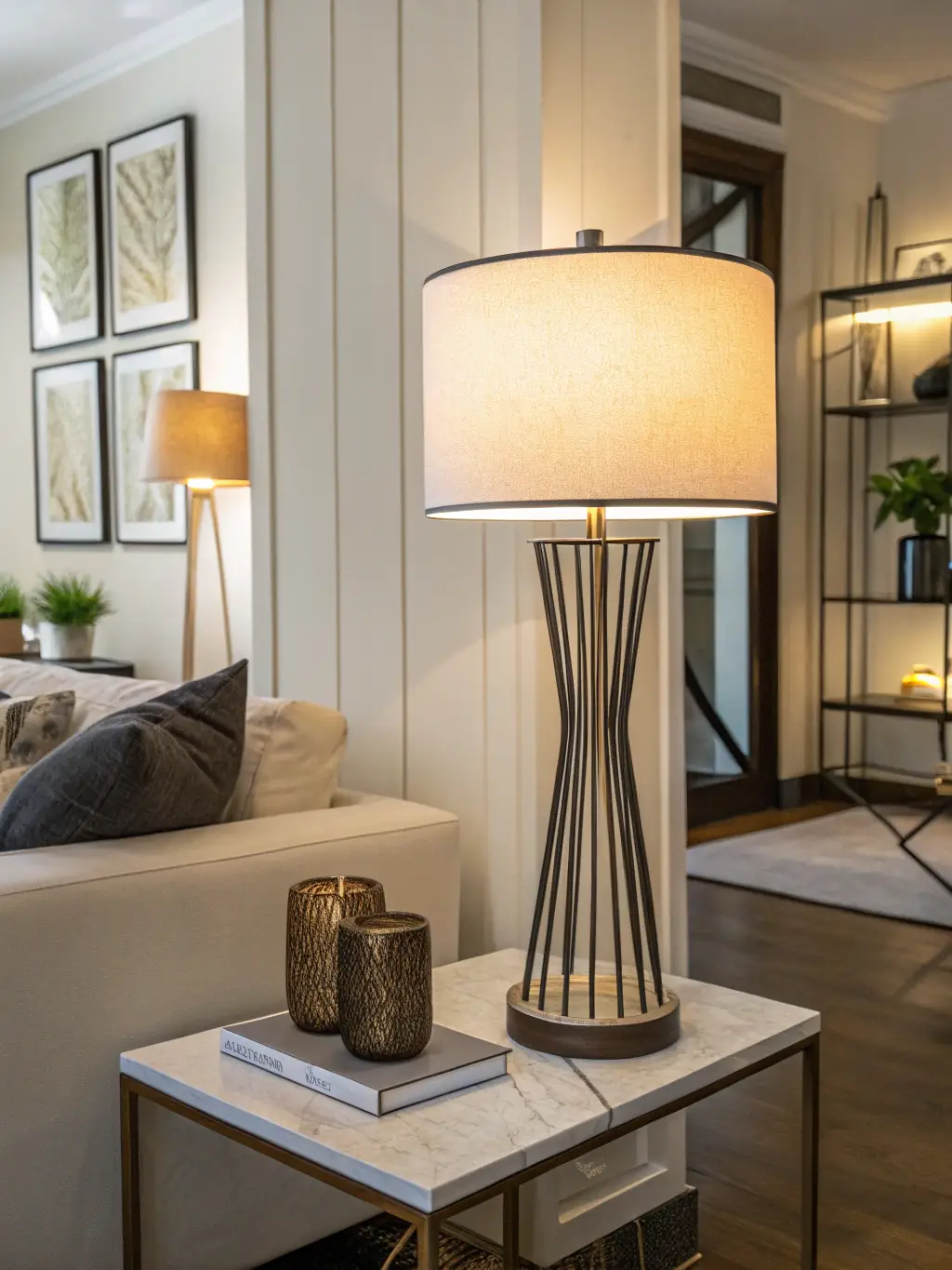 A stylish, modern table lamp with a ceramic base and a linen lampshade, casting a warm glow in a dimly lit room. The lamp is placed on a wooden side table next to a stack of books, creating a cozy atmosphere for the 'Home Ambiance' website.